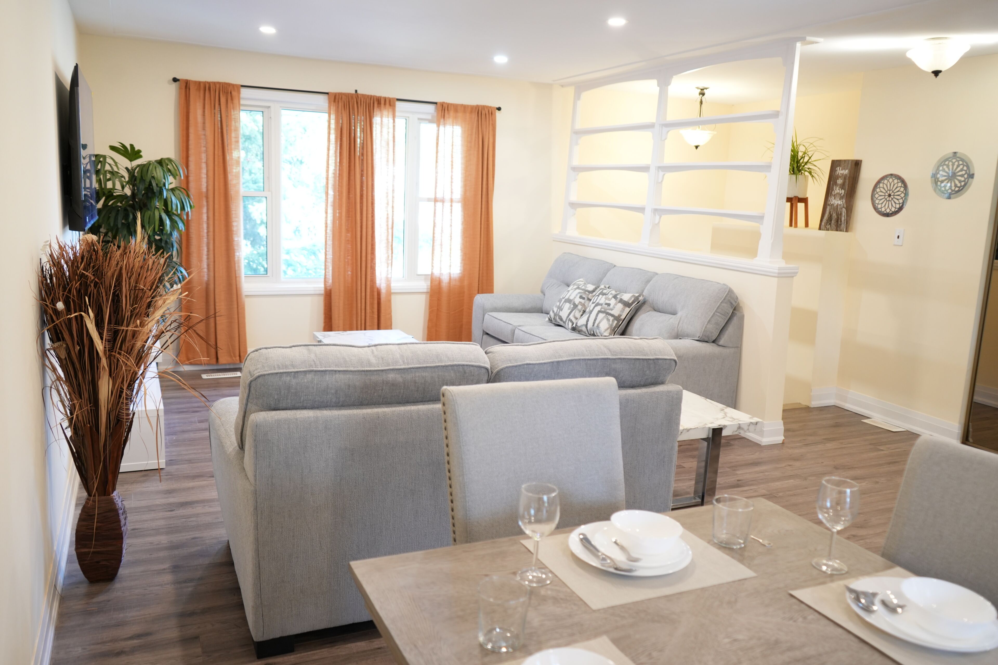A modern living room with a sofa, dining table, and a large window with curtains.