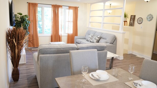 Un salon moderne avec un canapé, une table à manger et une grande fenêtre agrémentée de rideaux.