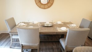 Une table à manger pour quatre personnes, avec des chaises, un miroir au mur et un plancher en bois.
