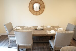 A dining table set for four with chairs, a mirror on the wall, and a wooden floor. - Peaceful Kitchener Getaway 5BR Home w/ BBQ & Modern Kitchen (Kitchener)
