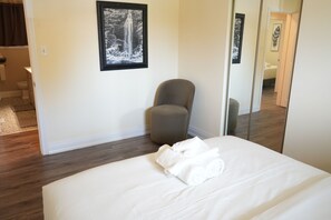 A hotel room with a bed, a chair, a mirror, and a framed picture on the wall. - Peaceful Kitchener Getaway 5BR Home w/ BBQ & Modern Kitchen (Kitchener)