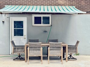 A patio with a table and chairs, a door, and a window. - Peaceful Kitchener Getaway 5BR Home w/ BBQ & Modern Kitchen (Kitchener)