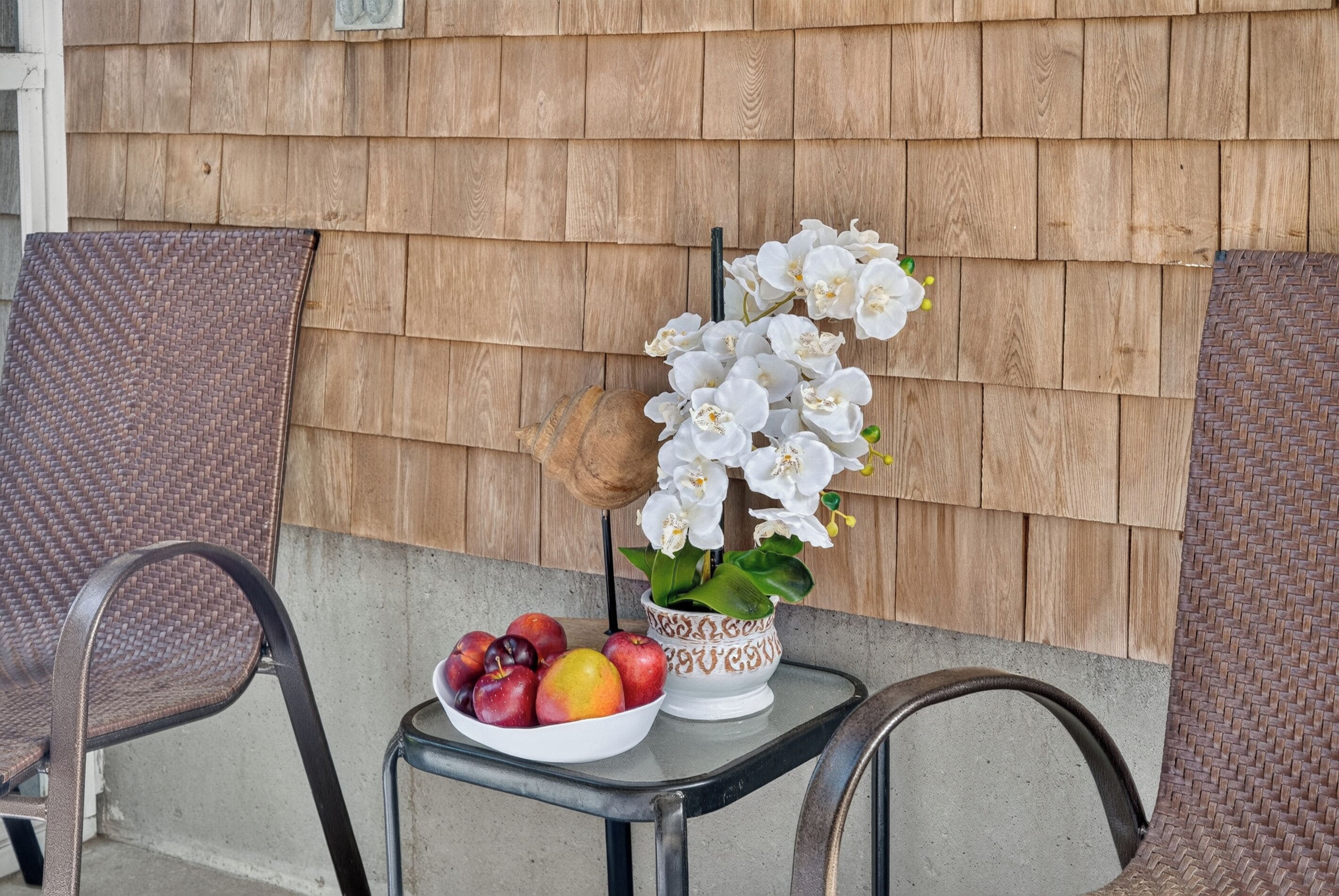 A table with a bowl of fruit and a potted orchid.