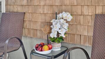A table with a bowl of fruit and a potted orchid.