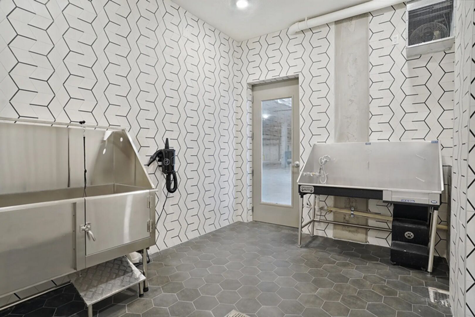 A bathroom with a hexagonal tile floor, a white sink, a mirror, and a shower area.