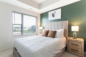 Ein modernes Hotelzimmer mit einem großen Bett, zwei Nachttischen und Blick aus dem Fenster.