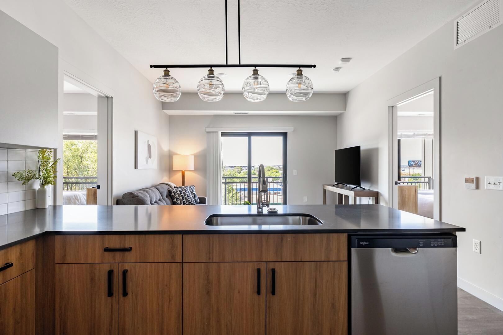 Una cocina moderna con una isla central, electrodomésticos de acero inoxidable y una zona de comedor con sofá y lámpara.