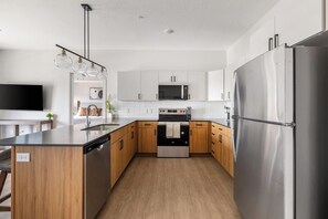 Eine moderne Küche mit Edelstahlgeräten, Holzschränken und einer zentralen Kochinsel.