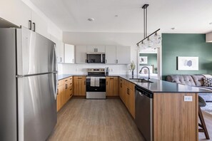 Une cuisine moderne dotée d’appareils électroménagers en acier inoxydable, de meubles en bois et d’un îlot central.