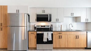 Eine moderne Küche mit Edelstahlgeräten, Holzschränken und einer weißen Fliesenspritzschutzleiste.