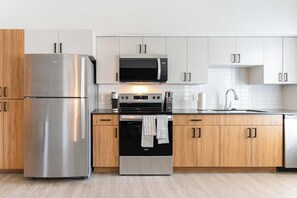 Uma cozinha moderna com eletrodomésticos de aço inoxidável, armários de madeira e um revestimento de azulejos brancos.