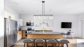 A modern kitchen with a central island, stainless steel appliances, and a dining area with bar stools. - Landing | Spectacular 2BD, Pool, Yoga Studio (Salt Lake City)
