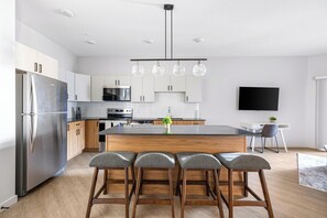 A modern kitchen with a central island, stainless steel appliances, and a dining area with bar stools. - Landing | Spectacular 2BD, Pool, Yoga Studio (Salt Lake City)