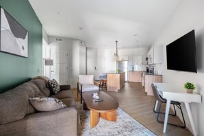 A modern living room with a sofa, coffee table, and dining area. - Landing | Spectacular 2BD, Pool, Yoga Studio (Salt Lake City)