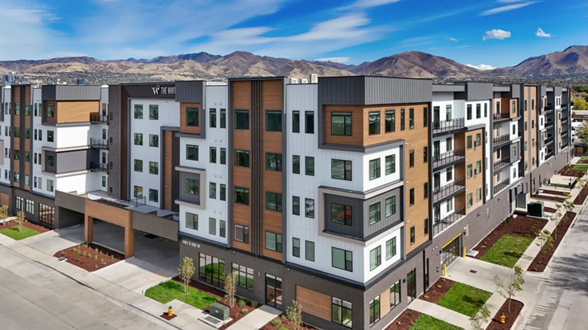 Un edificio residencial de varios pisos con un diseño moderno, que cuenta con balcones, ventanas grandes y un techo plano.