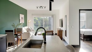 A modern living space with a kitchen island, seating area, and a large window providing a view of the outdoors. - Landing | Chic 1BD - One Bedroom Apartment, Sleeps 2 (Nashville)