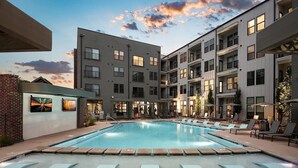 Um hotel moderno com piscina, espreguiçadeiras e uma parede de tijolos com obras de arte.