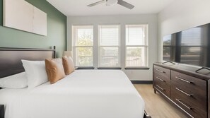 Ein Schlafzimmer mit einem Bett, einem Schminktisch und einem Deckenventilator.