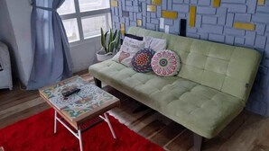 A living room with a green sofa, a red rug, and a patterned coffee table. - Abrisam Shareeah Family Homestay (Yogyakarta)