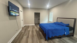 A bedroom with a bed, a TV mounted on the wall, and a walk-in closet. - Matthews Blue house spacious 5BD and 2BA in calm neighborhood (Wilmer)