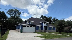 A two-story house with a garage, a driveway, and a grassy lawn. - Matthews Blue house spacious 5BD and 2BA in calm neighborhood (Wilmer)