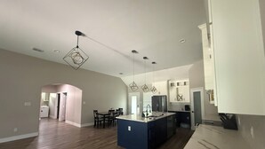 A spacious kitchen with a central island, wooden flooring, and pendant lighting. - Matthews Blue house spacious 5BD and 2BA in calm neighborhood (Wilmer)