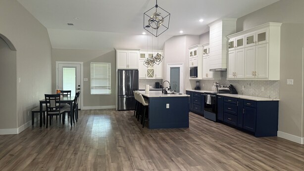 A modern kitchen with a central island, built-in appliances, and a dining area with chairs. - Matthews Blue house spacious 5BD and 2BA in calm neighborhood (Wilmer)