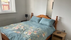 Un dormitorio con cama, mesita de noche y lámpara.