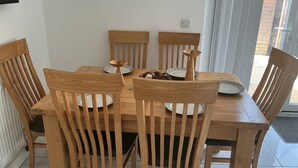 Un comedor con una mesa y sillas de madera, un pequeño objeto decorativo sobre la mesa y vistas al exterior a través de un ventanal.