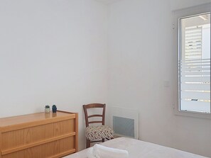 A bedroom with a wooden dresser, a chair, a bed, and a window with blinds. - Coeur d'Oléron by Interhome (Ile d'Oléron)