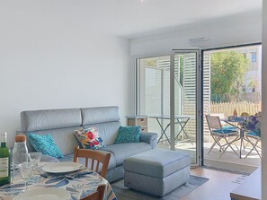 A modern living room with a grey sofa, a small table, and a dining area. - Coeur d'Oléron by Interhome (Ile d'Oléron)