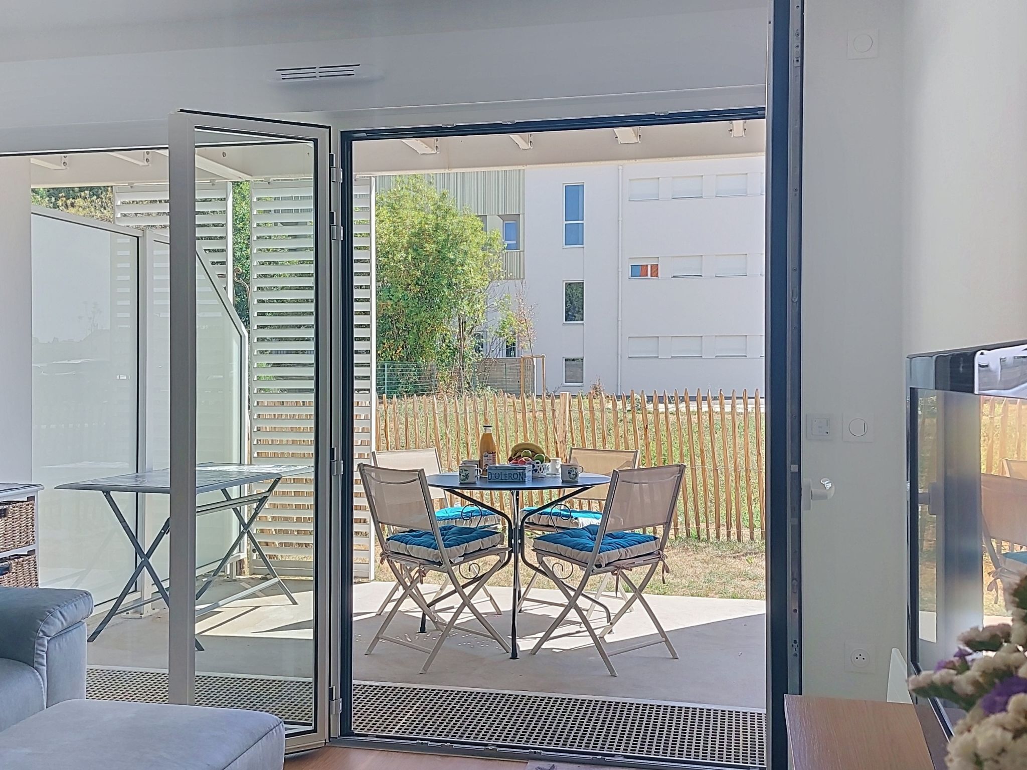 Habitación moderna con puerta de vidrio corredera que da a un patio exterior con mesa y sillas.