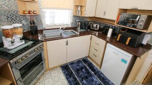 Kompakti keittiö, jossa on kaasuliesi, uuni, mikroaaltouuni, leivänpaahdin ja pieni jääkaappi.