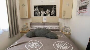 Een slaapkamer met een bed, een spiegel en een poster aan de muur.