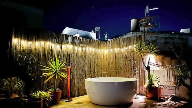 Uma área de spa com uma banheira grande, parede de bambu e plantas em vasos.