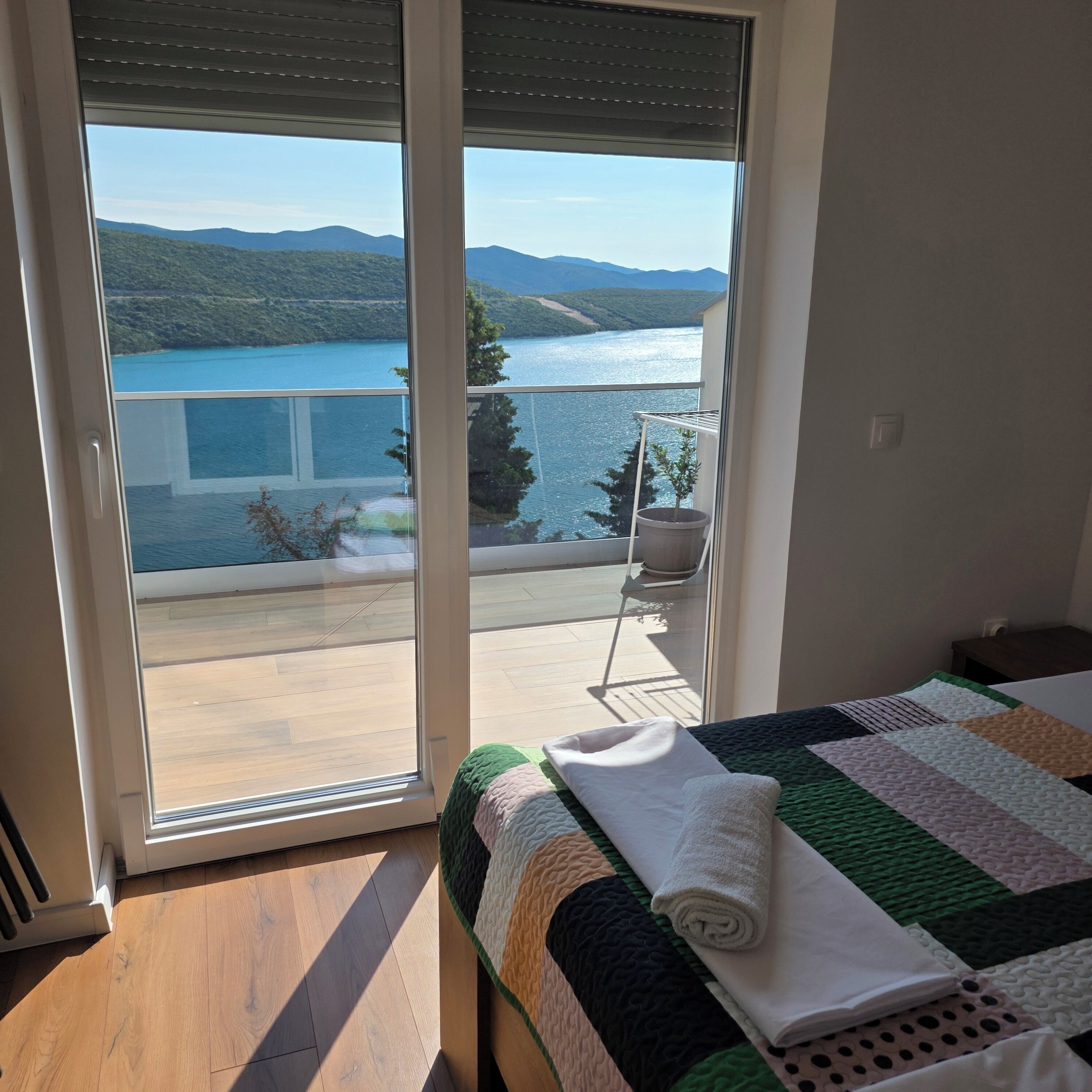 Ein Schlafzimmer mit Bett, Seeblick und einem Balkon mit Stuhl.
