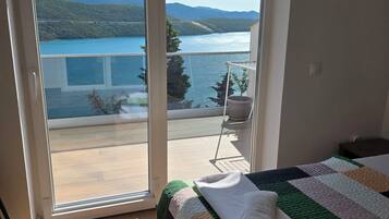 Ein Schlafzimmer mit Bett, Seeblick und einem Balkon mit Stuhl.
