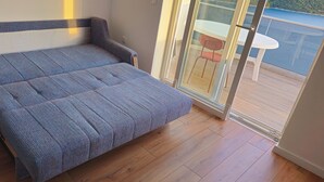 Quarto com cama, porta de correr de vidro que dá para área externa com mesa e cadeiras.