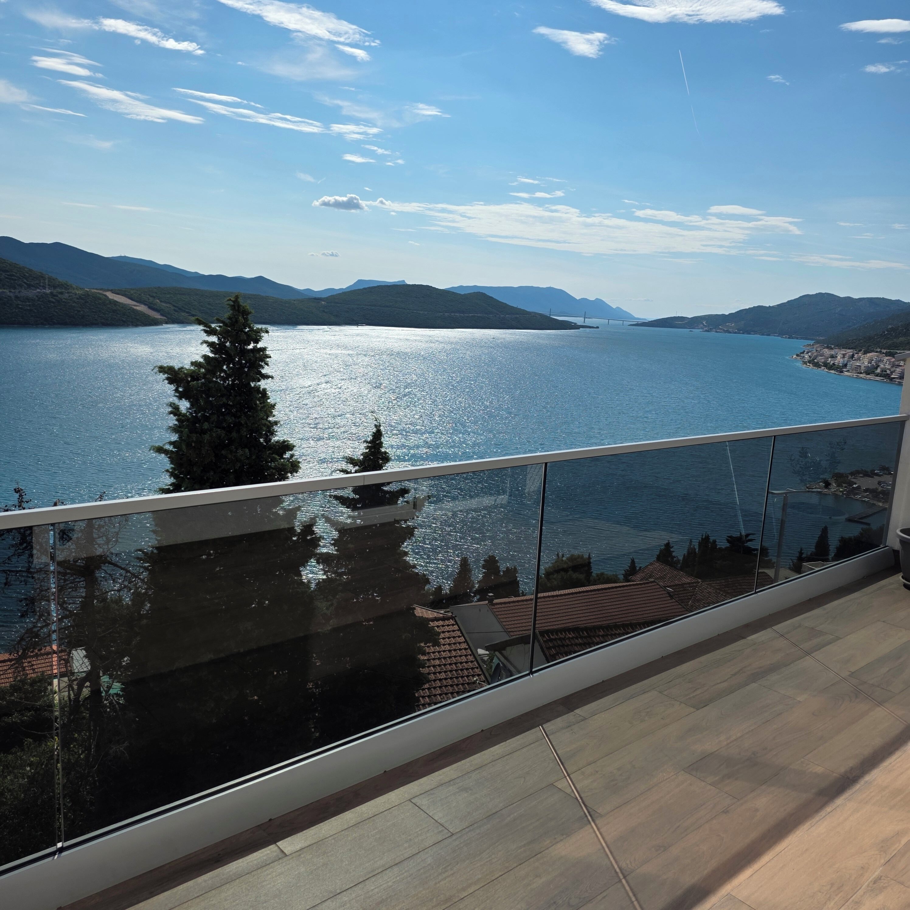 Ein Balkon mit Blick auf einen See, Berge und eine Brücke.