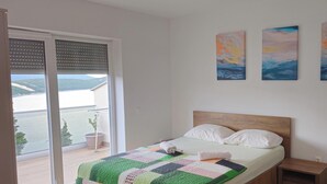 Quarto com cama, mesa de cabeceira e vista para o exterior por uma porta deslizante.
