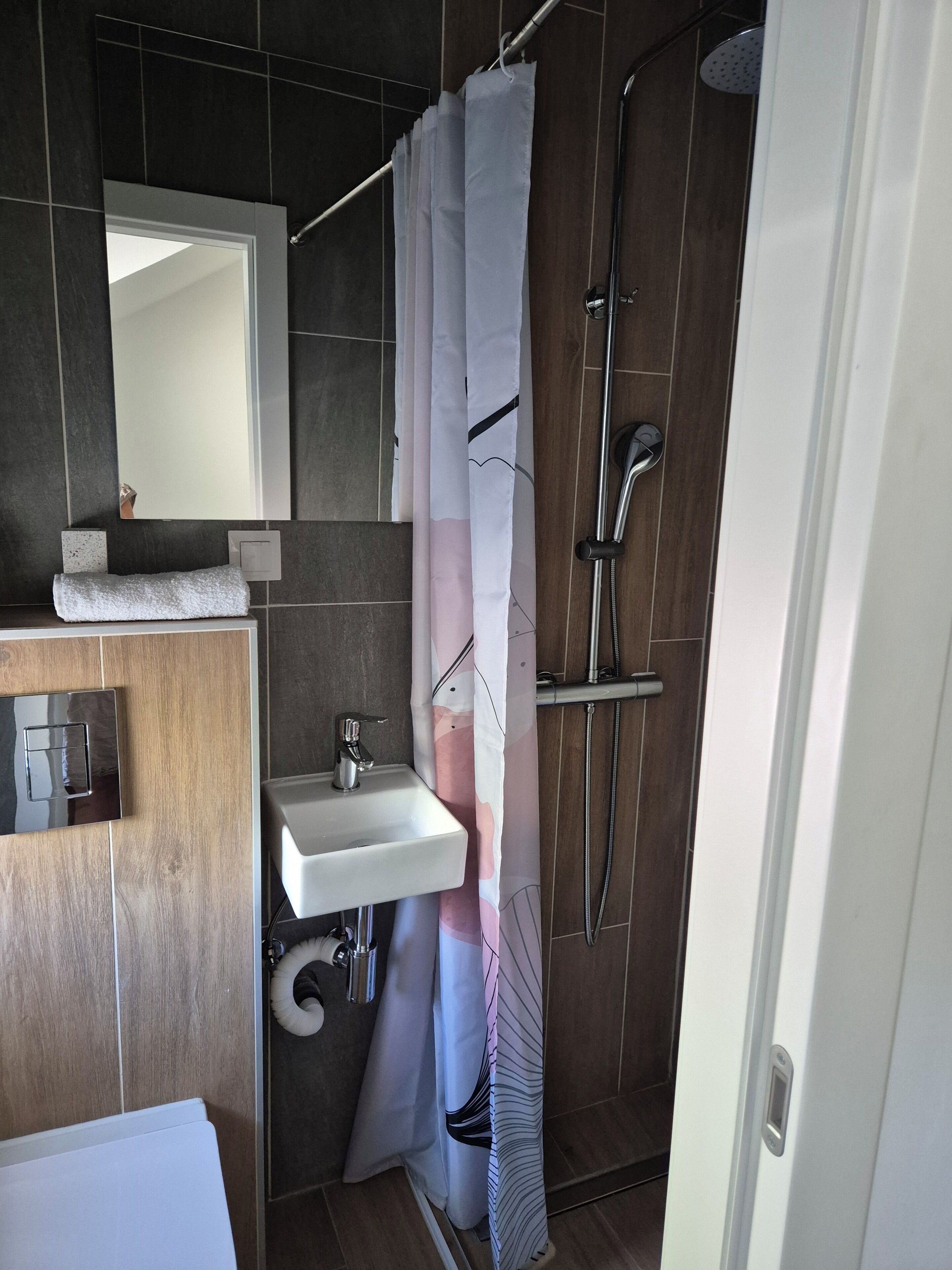Ein modernes Badezimmer mit Dusche, Waschbecken und Spiegel.