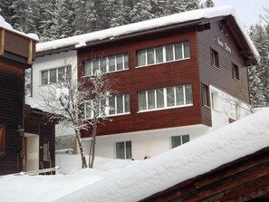 Ein mehrstöckiges Gebäude mit Holzfassade und weißem Zierdekor.