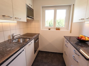 A compact kitchen with a stainless steel sink, a built-in oven, and a window with a view of greenery. - Azur Appartement/Fewo 4-Bettwohnung Nr. 2 by Interhome (Saas-Fee)