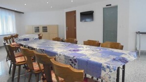 A conference room with a long table, wooden chairs, a cabinet, and a door. - Weideli Appartement/Fewo 6 Bettwohnung Nr. 21 by Interhome (Saas-Grund)