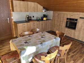 Una cocina compacta con armarios de madera, una mesa de comedor con sillas y un horno empotrado.