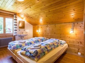 Ein Schlafzimmer einer Holzhütte mit Bett, Fenster, Heizkörper und Spüle.