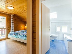 L’intérieur d’un chalet en bois comprend un lit, une salle de bain avec des toilettes et une fenêtre.