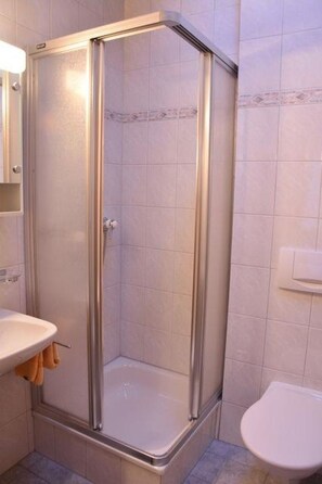 Ein Badezimmer mit einer Duschkabine, einem Waschbecken und einer Toilette.