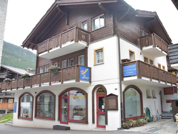 Ein mehrgeschossiges Gebäude mit Balkonen, großen Fenstern und einer Schau für einen Skiservice.