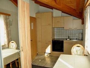 Eine kleine Küche mit Holzausstattung, einer gefliesten Spritzschutzleiste und einem schwarzen Backofen.